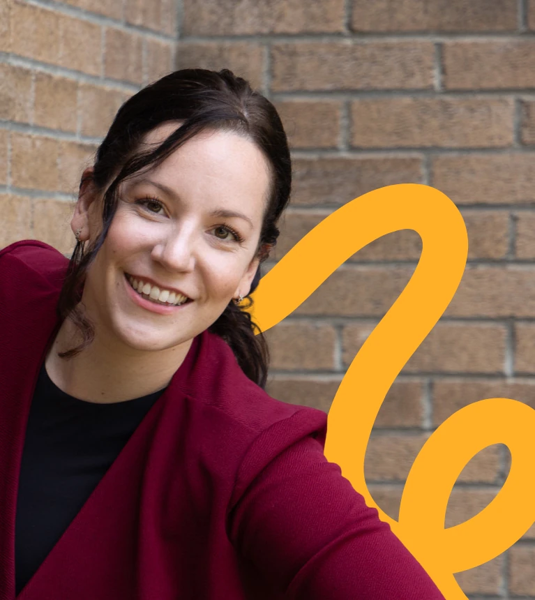 Erika, from Sédentaire, smiling in front of a brick wall